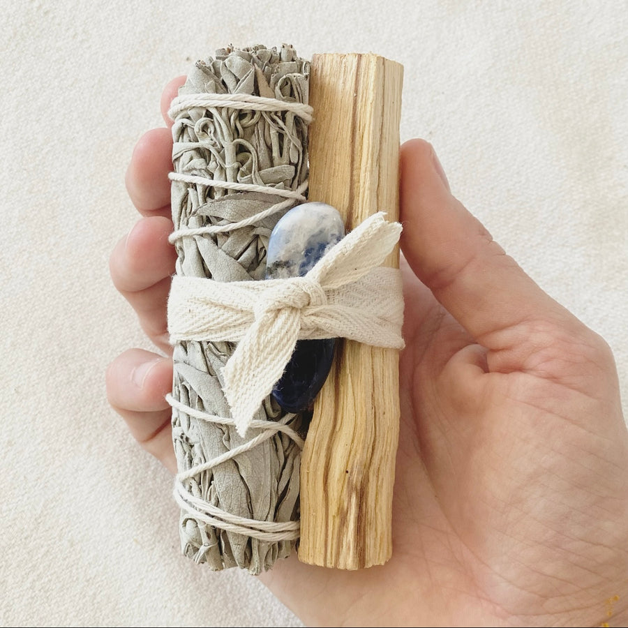 Ritual-Set True Self mit Palo Santo, weisser Salbei, Sodalith Edelstein mit Baumwollband in der Hand liegend